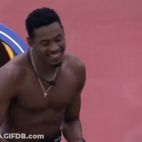 Shirtless Man In Necklace Smiling On Red Surface GIF