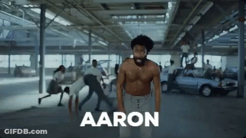 Shirtless Man In Parking Garage Surrounded By People GIF