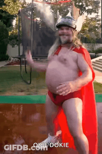 Shirtless Man In Red Cape And Helmet Dancing On Trampoline Saying Okie Dokie GIF
