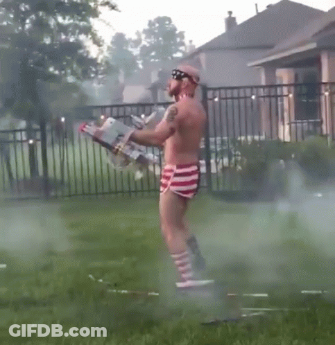 Shirtless Man In Red White And Blue Shorts Holding Flamethrower GIF