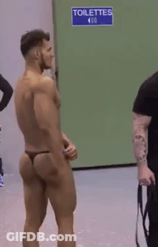 Shirtless Man In Thong In Front Of Blue Toilettes Sign GIF