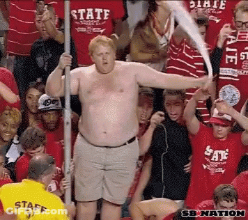 Shirtless Man In Yellow Staff Shirt In Front Of Crowd GIF
