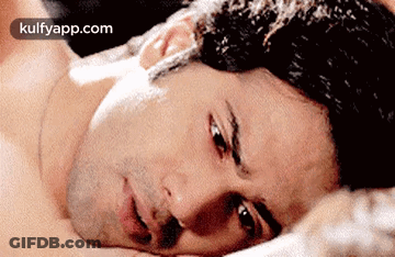 Shirtless Man Lying On Bed Looking At Camera GIF