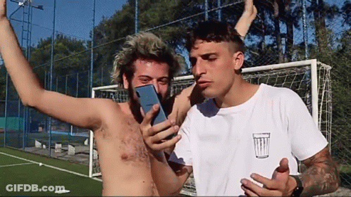 Shirtless Man Photographing Another Shirtless Man With Trash Can GIF