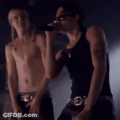 Shirtless Man Singing Into Microphone Next To Another Man GIF
