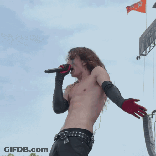Shirtless Man Singing Into Microphone With Black Gloves GIF