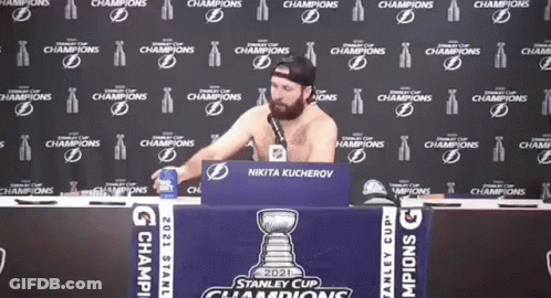 Shirtless Man Sitting At Table With Stanley Cup Sign GIF