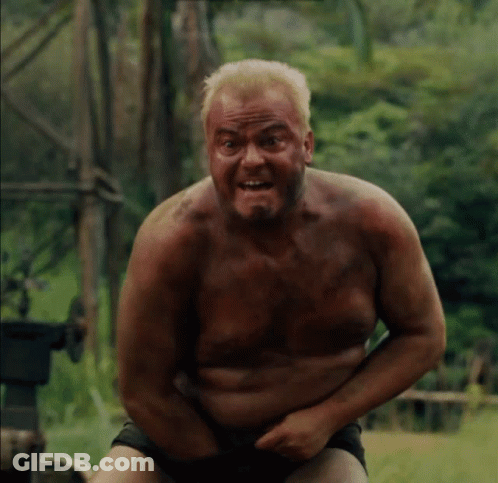 Shirtless Man Sitting In Field With Hands On Stomach GIF