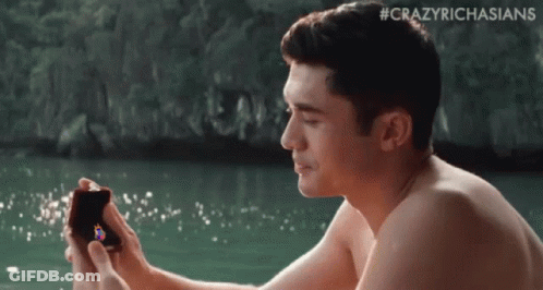 Shirtless Man Sitting In Water Holding Box With Ring GIF