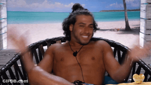 Shirtless Man Sitting On Beach With Arms Outstretched GIF