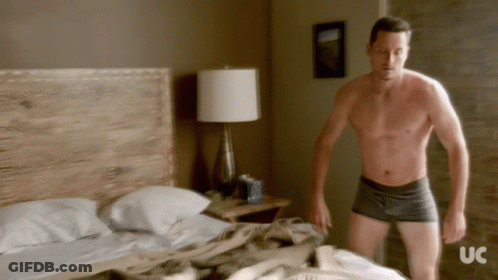 Shirtless Man Standing In Front Of Bed With UC GIF