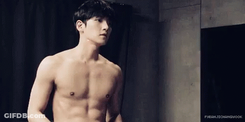Shirtless Man Standing In Front Of Black Curtain GIF