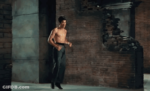 Shirtless Man Standing In Front Of Brick Wall GIF