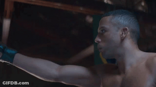 Shirtless Man Standing In Front Of Flag With Letter O GIF