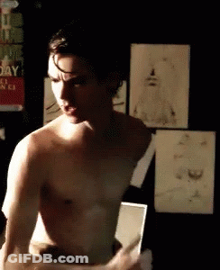 Shirtless Man Standing In Front Of Mirror In Dark Room GIF
