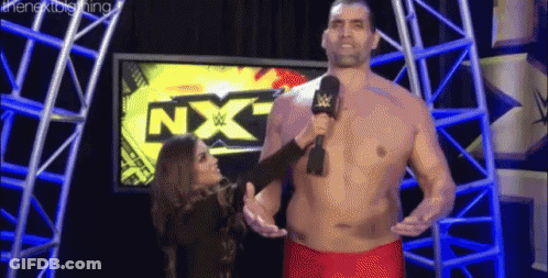 Shirtless Man Talking Into Microphone With Woman Behind Him GIF