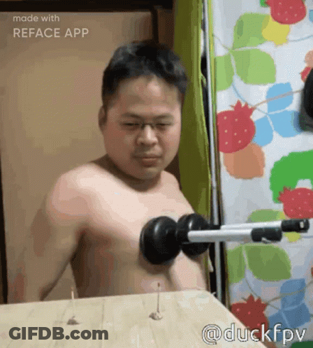 Shirtless Man Using Dumbbell On Wooden Table GIF