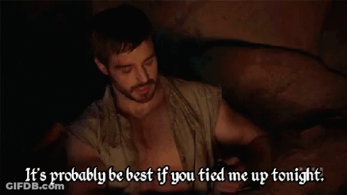 Shirtless Man With Beard Sitting In Dark Room GIF