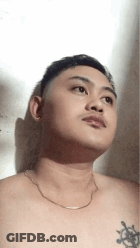 Shirtless Man With Chest Tattoo And Chain Looking Up GIF