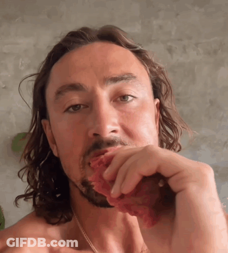 Shirtless Man With Long Hair Eating Meat GIF