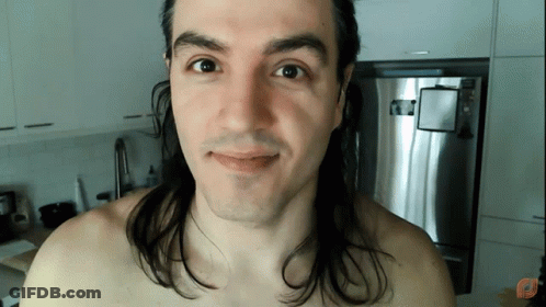 Shirtless Man With Long Hair Smiling In Front Of Refrigerator GIF