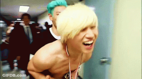 Shirtless Man With Medal Laughing With Another Man GIF