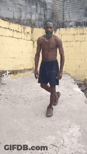 Shirtless Man With Mustache And Necklace Walking Down Sidewalk GIF