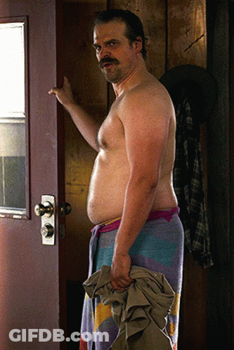 Shirtless Man With Mustache Holding Towel In Doorway GIF