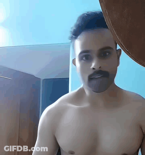 Shirtless Man With Mustache Standing In Front Of Blue Wall GIF