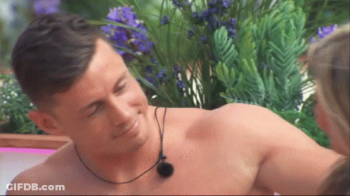 Shirtless Man With Necklace Smiling At Woman GIF