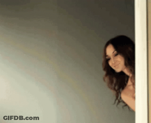 Shirtless Woman Peeking From Doorway Smiling GIF