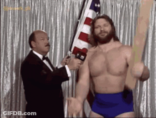 Shirtless Wrestler Holding Flag Interviewed By Tuxedo Man GIF