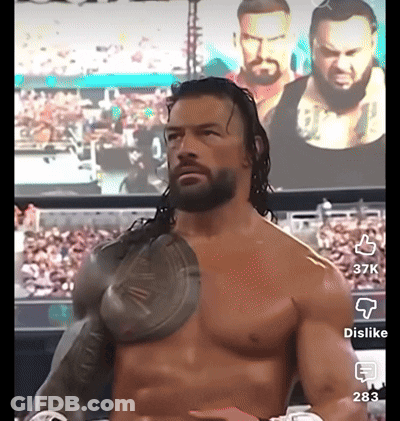 Shirtless Wrestler In Front Of Roman Reigns Screen GIF