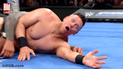 Shirtless Wrestler Lying In Front Of Live Sign GIF
