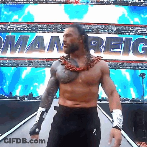 Shirtless Wrestler Walking Down Ramp With Roman Reigns Behind Him GIF