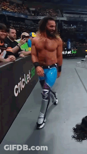 Shirtless Wrestler Walking Past Cricket Sign GIF