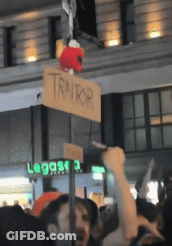 Sign Saying Traitor Hanging From Pole GIF