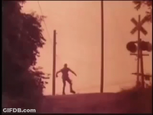 Silhouette Of Person At Railroad Crossing Sunset GIF