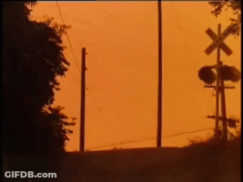Silhouette Of Person Next To Railroad Crossing GIF