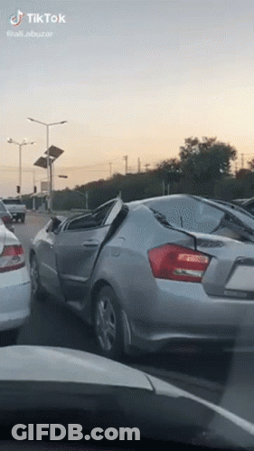 Silver Car With Broken Windshield Driving On Street GIF