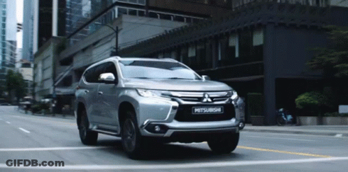 Silver Mitsubishi SUV Driving On City Street GIF