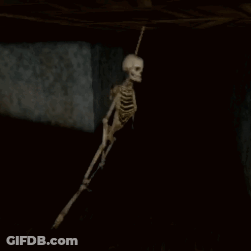 Skeleton Hanging From Ceiling In Dark Cave GIF