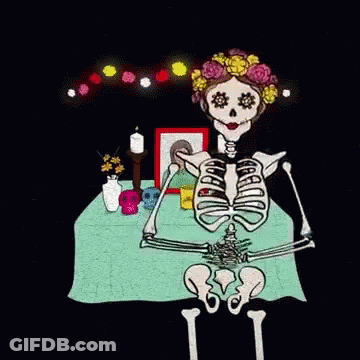 Skeleton Sitting At Table With Skulls And Flowers GIF