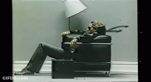 Skeleton Sitting In Chair With Lamp On Head GIF