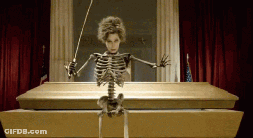 Skeleton Sitting In Coffin Holding Baton GIF