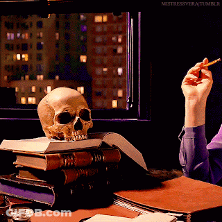 Skull On Stack Of Books And Hand Holding Cigarette GIF