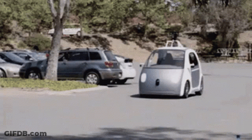 Small White Car Driving Down Street GIF