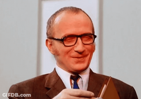 Smiling Man In Glasses And Suit Holding Book GIF