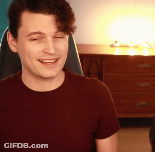 Smiling Man In Maroon Shirt Sitting In Chair GIF
