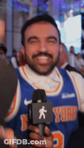 Smiling Man In New York Knicks Jersey Holding Microphone GIF
